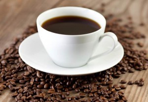cup of black coffee surrounded by coffee beans